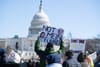 Protesters holding signs with US capitol in the background